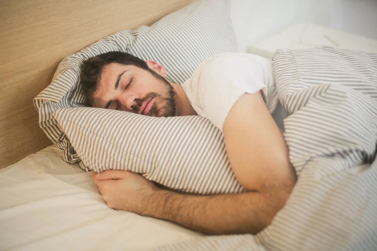 homme qui dort dans son lit avec un matelas pas cher